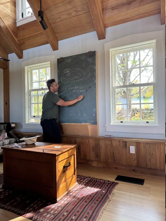 A lab member giving a chalk talk beside the farmhouse chalkboard